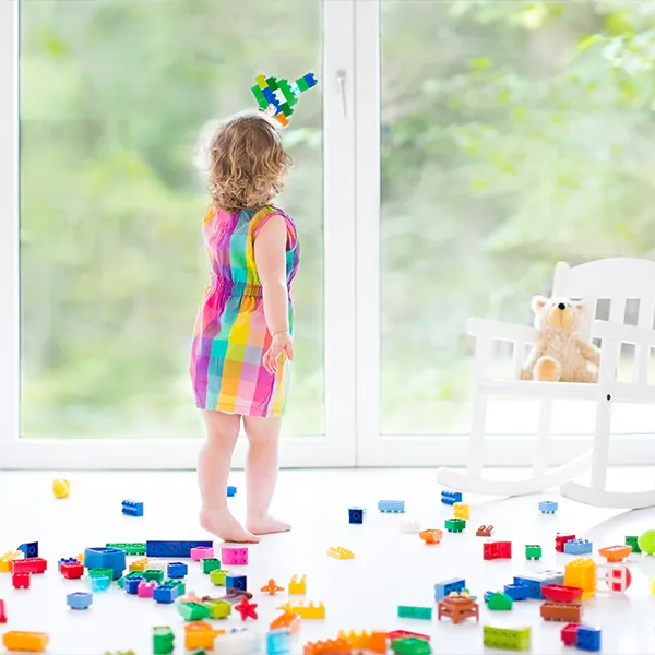 Kind spielt mit bunten Bausteinen vor einem wei&szlig;en PVC-Fenster