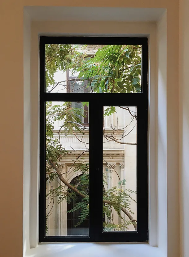 Anthrazitfarbenes Fenster in heller Wandnische mit Blick ins Grüne – modernes und elegantes Erscheinungsbild im Innenraum.