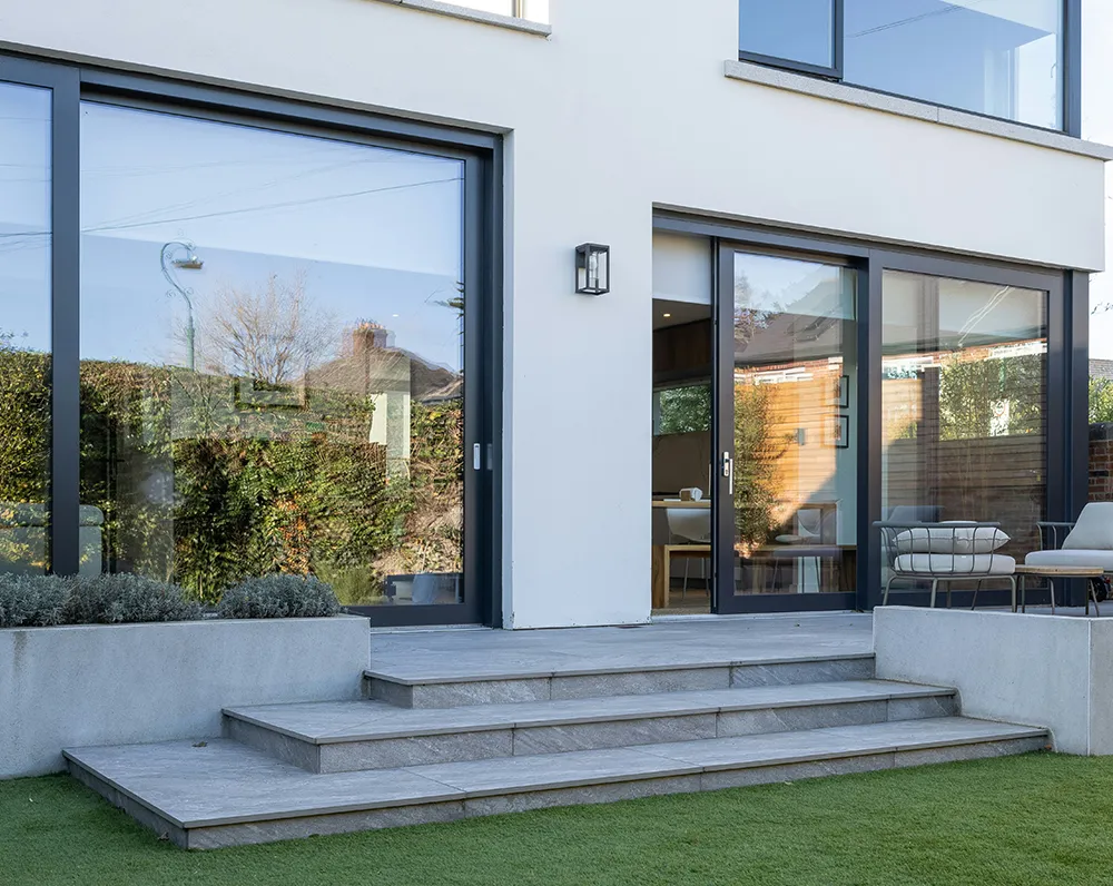 Modernes Einfamilienhaus mit großen anthrazitfarbenen Fenstern und Terrassentüren – elegante Fassadengestaltung im zeitgemäßen Baustil.