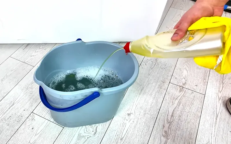 Sp&uuml;lmittel wird in einen Eimer mit warmem Wasser zur Vorbereitung der Fensterreinigung gegossen.