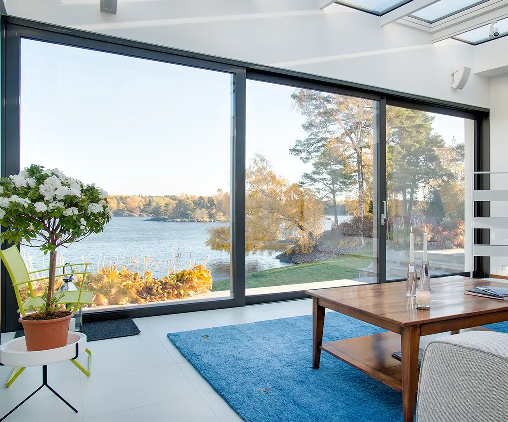 Große schwarze Schiebefenster mit Blick auf See und Garten – moderne Architektur mit klar betonter Gebäudeform.