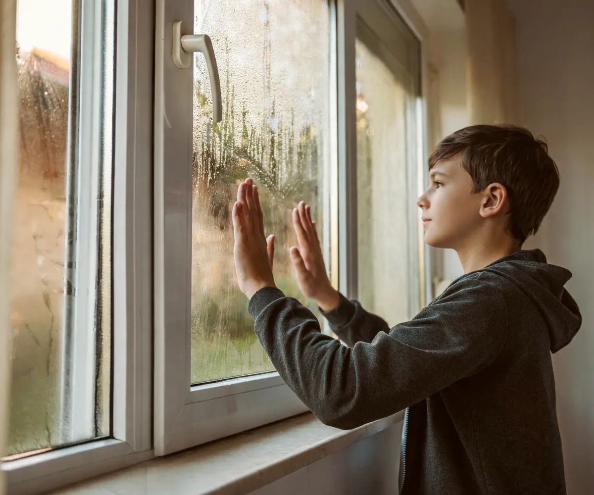 Kind ber&uuml;hrt eine beschlagene Fensterscheibe von innen &ndash; Kondensation entsteht durch Temperaturunterschied zwischen Innenraum und Au&szlig;enluft.