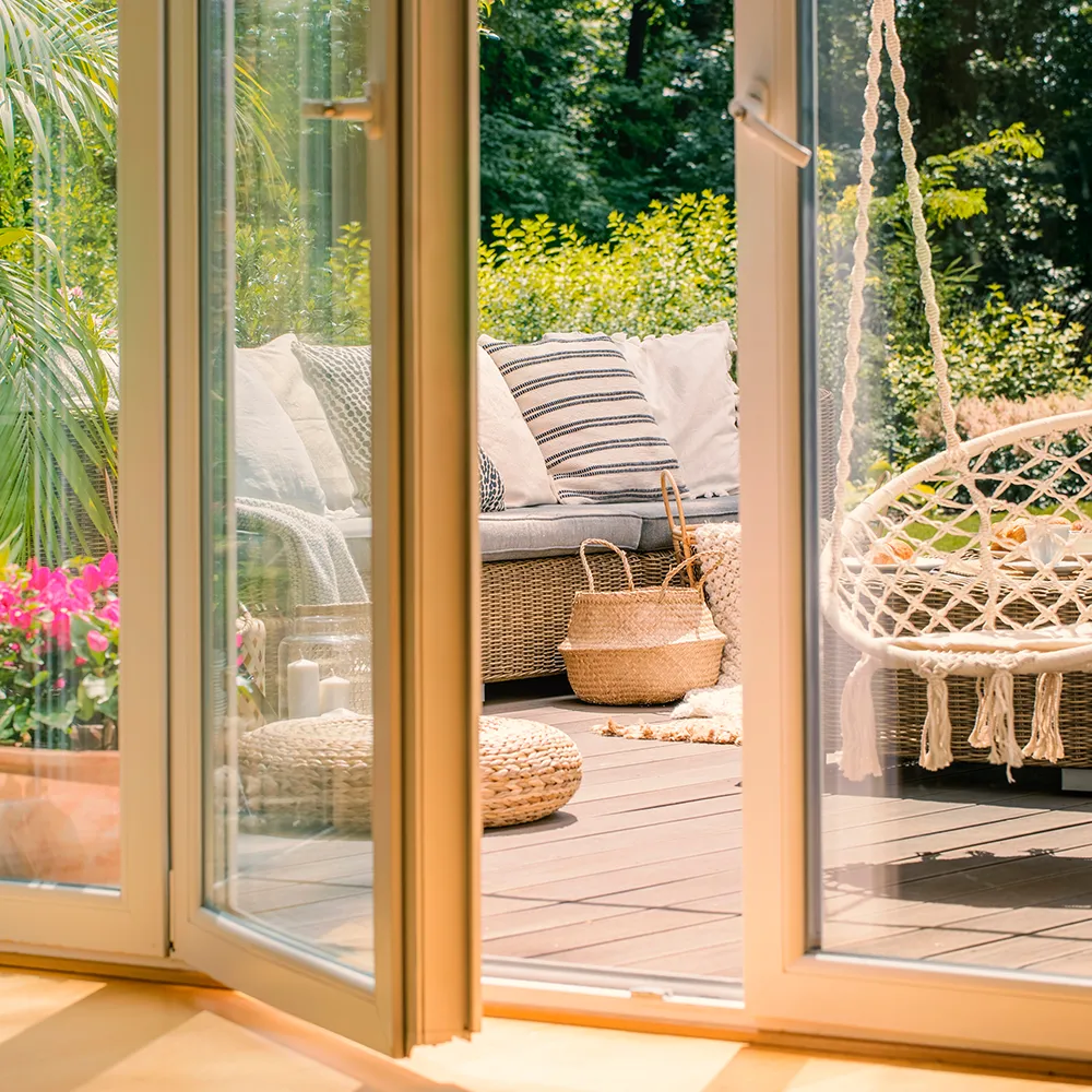 Geöffnete verglaste Balkontür mit Zugang vom Wohnraum zu einer Terrasse mit Sitzbereich