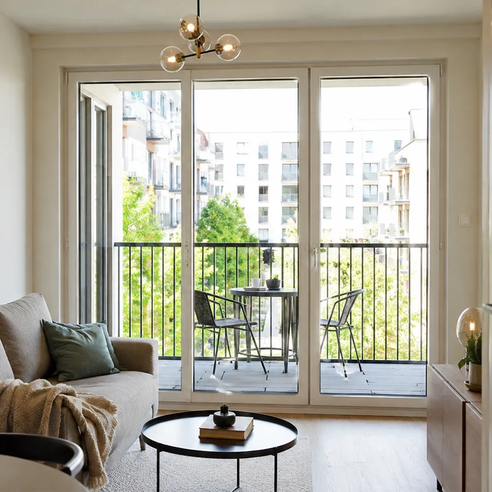 Nach innen geöffnete weiße Balkontür in einem kleinen Wohnzimmer, die zusätzlichen Platz vor dem Zugang zum Balkon beansprucht